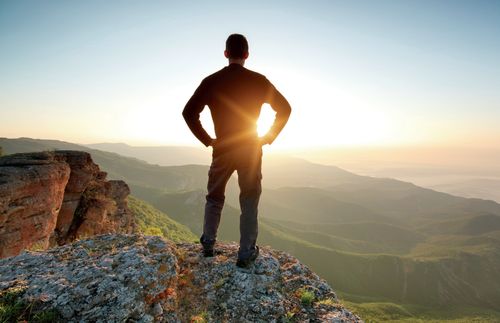 young man on a mountain top looking at mountains