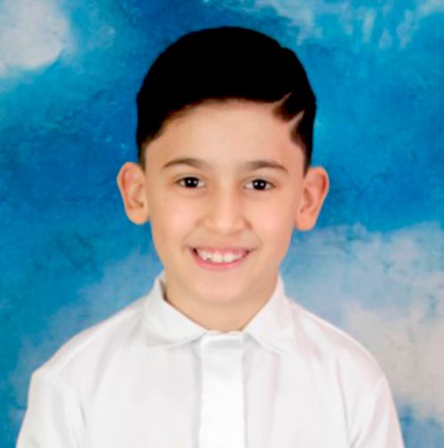 Gustavo Da Silvia dressed in baptismal clothes with a birthday cake for his 8th birthday