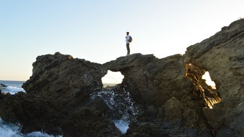 uma pessoa em cima de algumas pedras, olhando o mar