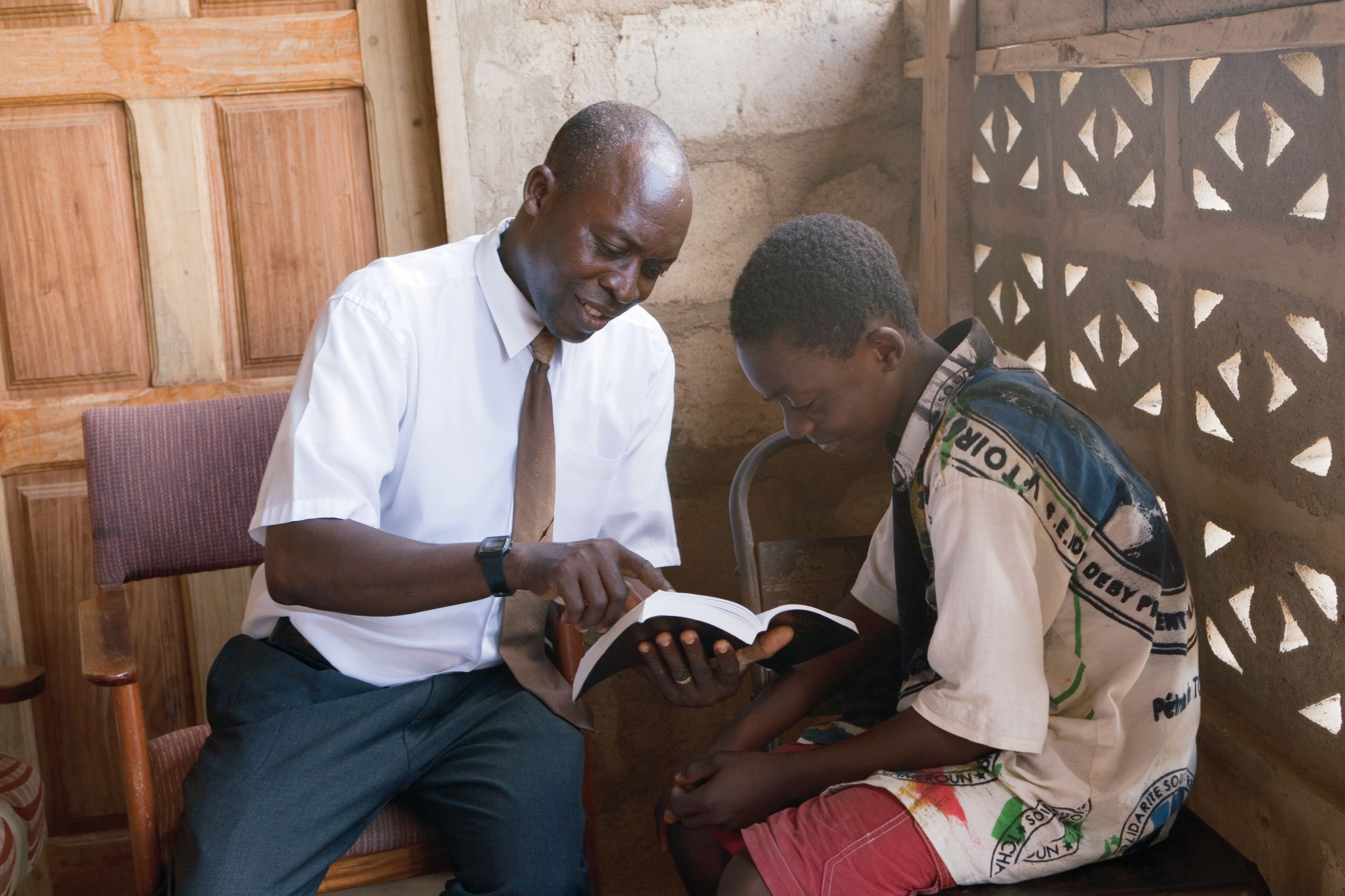 A father studies the scriptures with his son.