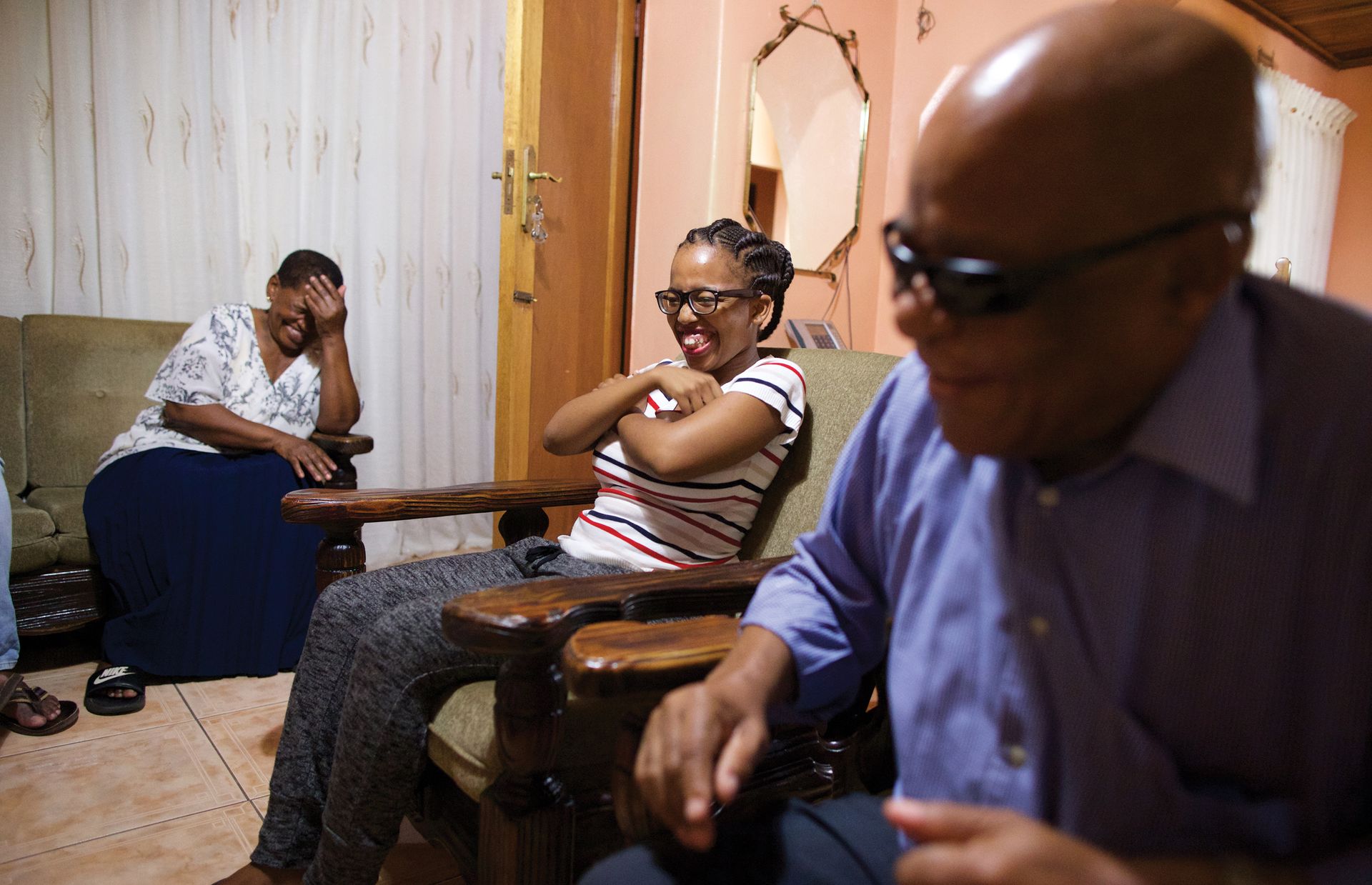 Naledi Modige (middle), a fellow ward member, laughs with Libuletswe and his wife, Makhosazana (far left), during family home evening. The Mokgatles love to have people in their home.