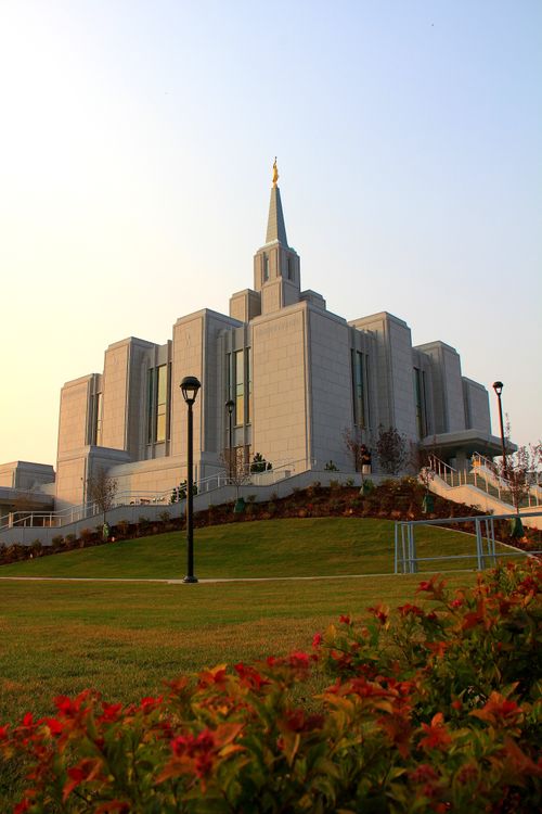 The Calgary Alberta Temple seen from the bottom of the hill, with orange plants and flowers in the foreground.
