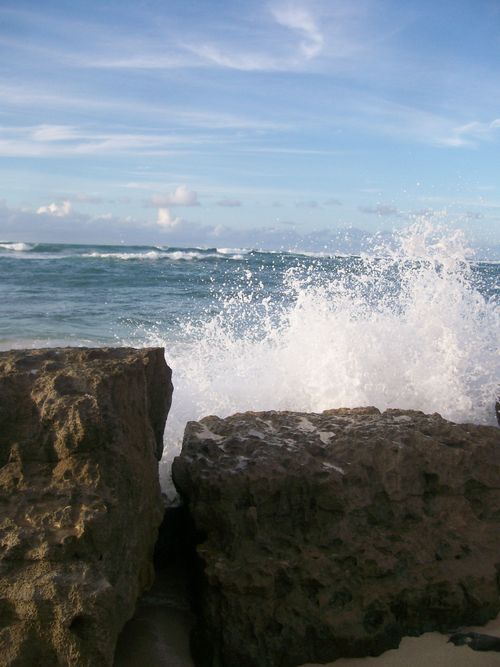 Waves crash on two cylindrical rocks in Hawaii.