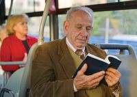 A Brazilian man reading the scriptures.  He is sitting on a bus.