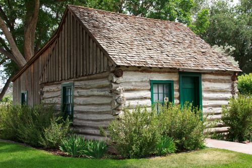 A log cabin with a green door standing on the grounds of Cove Fort in Utah.