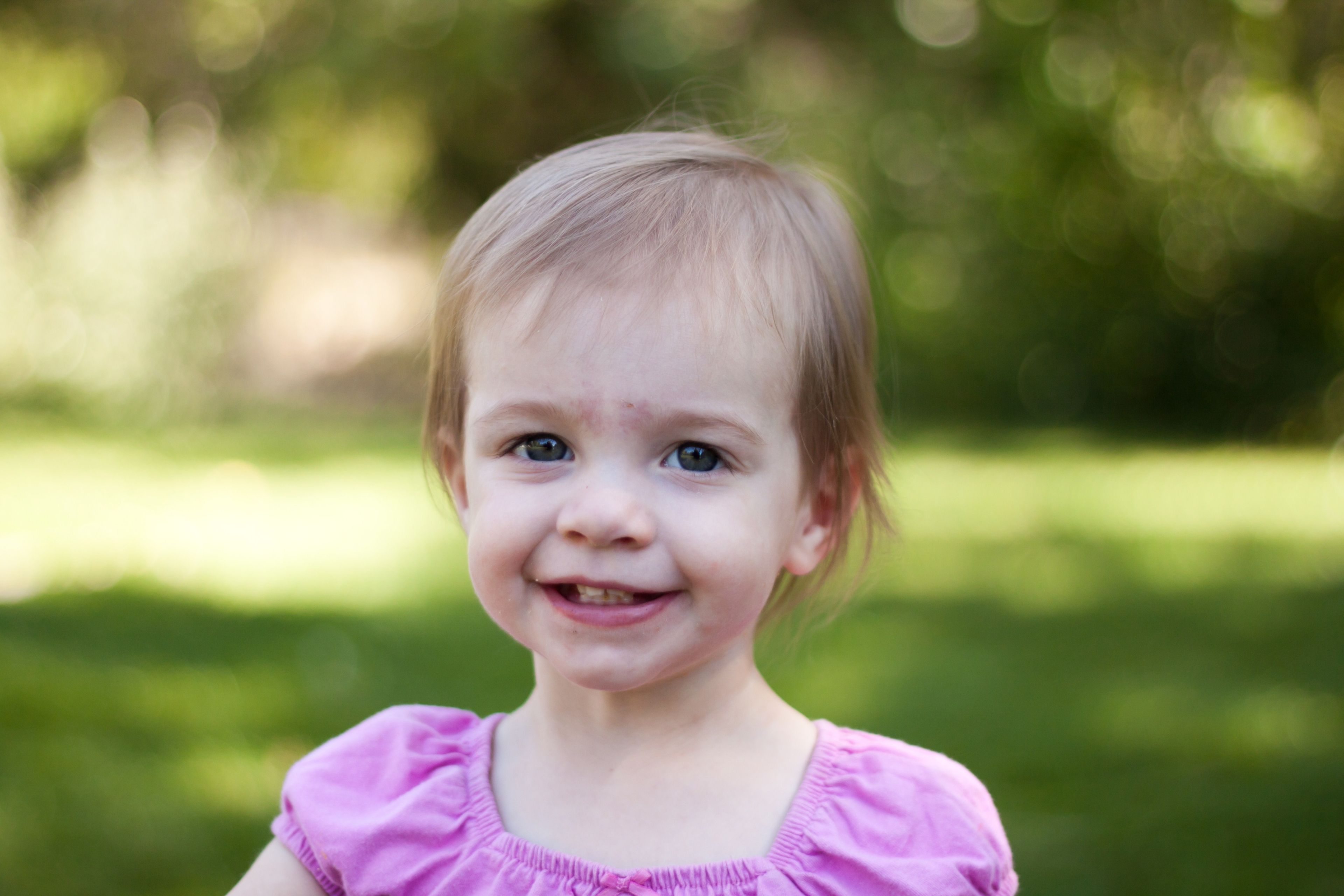 A toddler girl in a pink shirt, smiling.