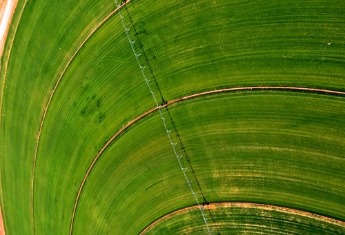 An aerial view of a water pivot on a circular green field.