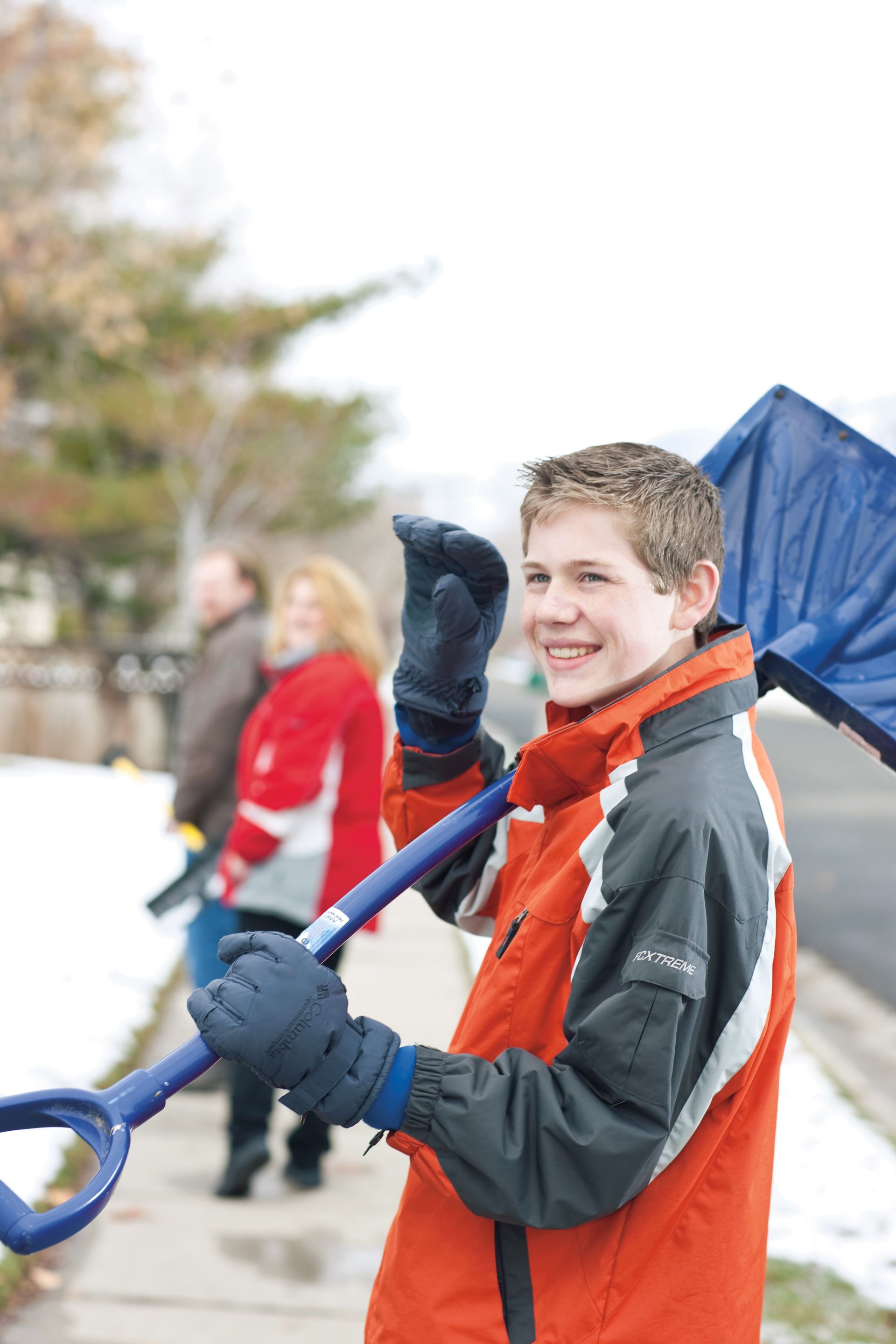 A young man carries a snow shovel on his shoulder while shoveling snow as service.