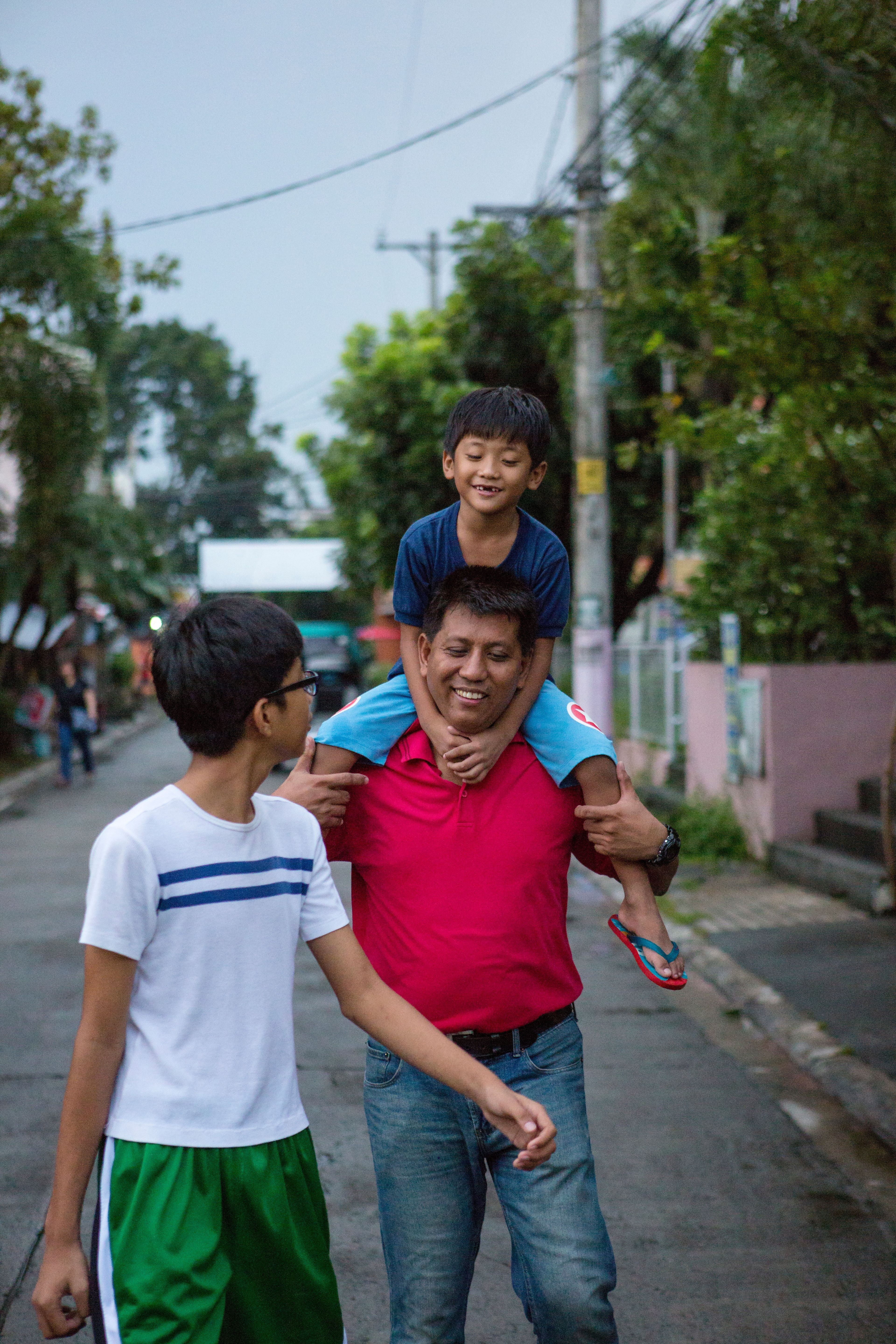 A father walks down the street with his two sons.