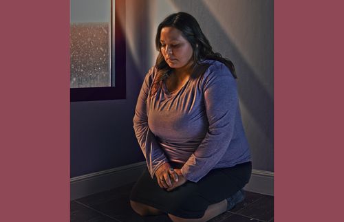 young woman kneeling in prayer