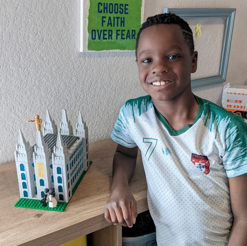 boy standing next to temple made of blocks