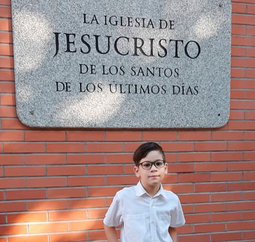 boy standing in front of Church sign