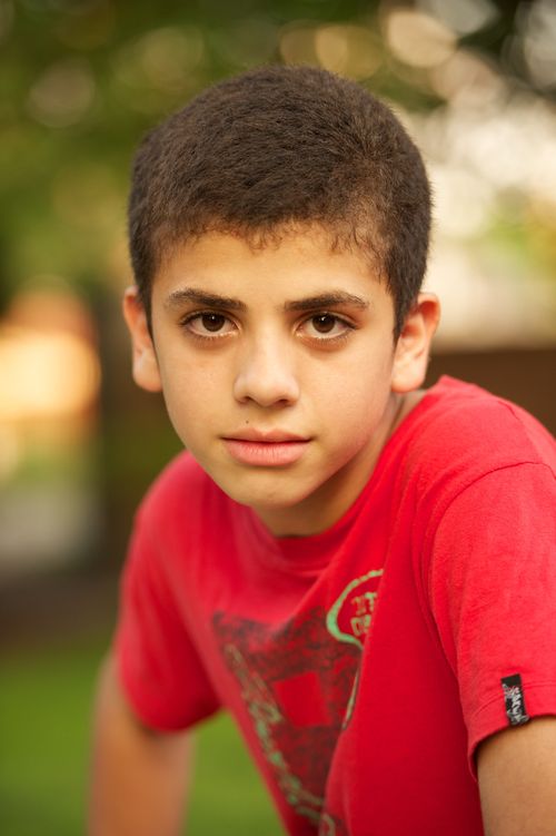 A head shot of a boy from Argentina with dark brown hair, wearing a red T-shirt.