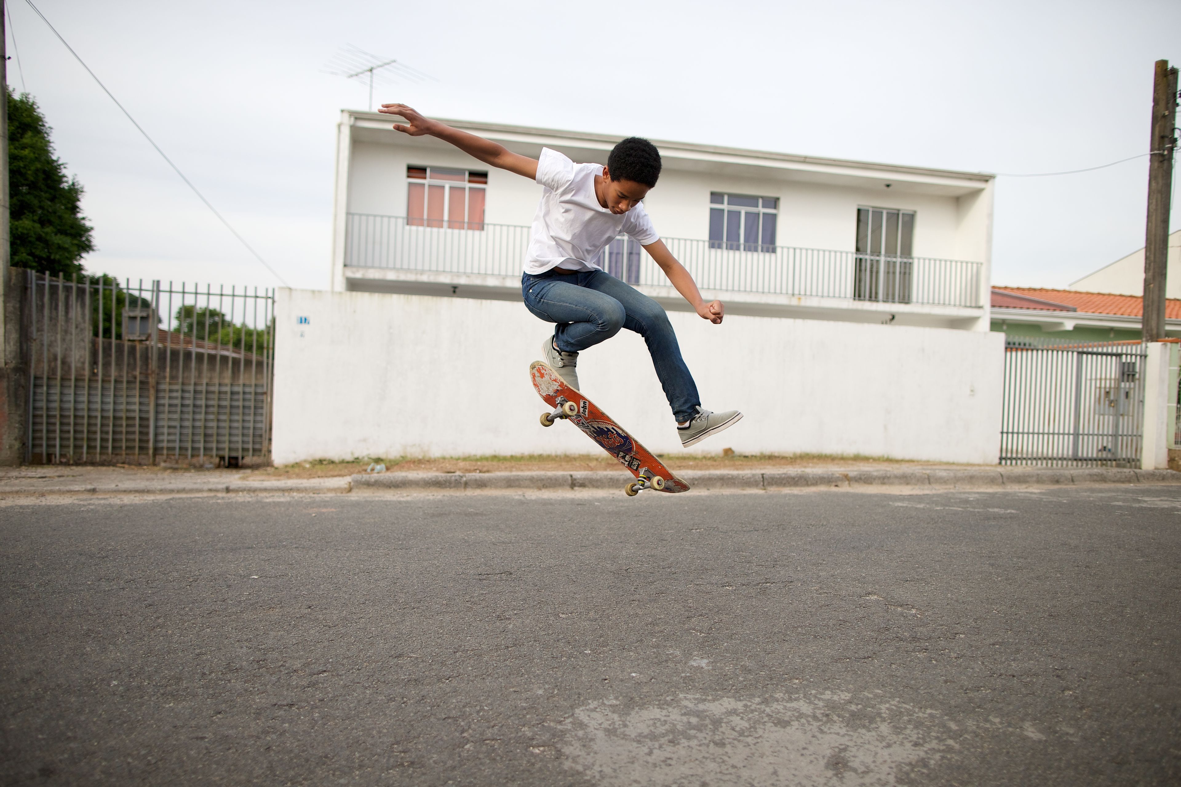 A young man from Brazil does a skateboard trick in a street.