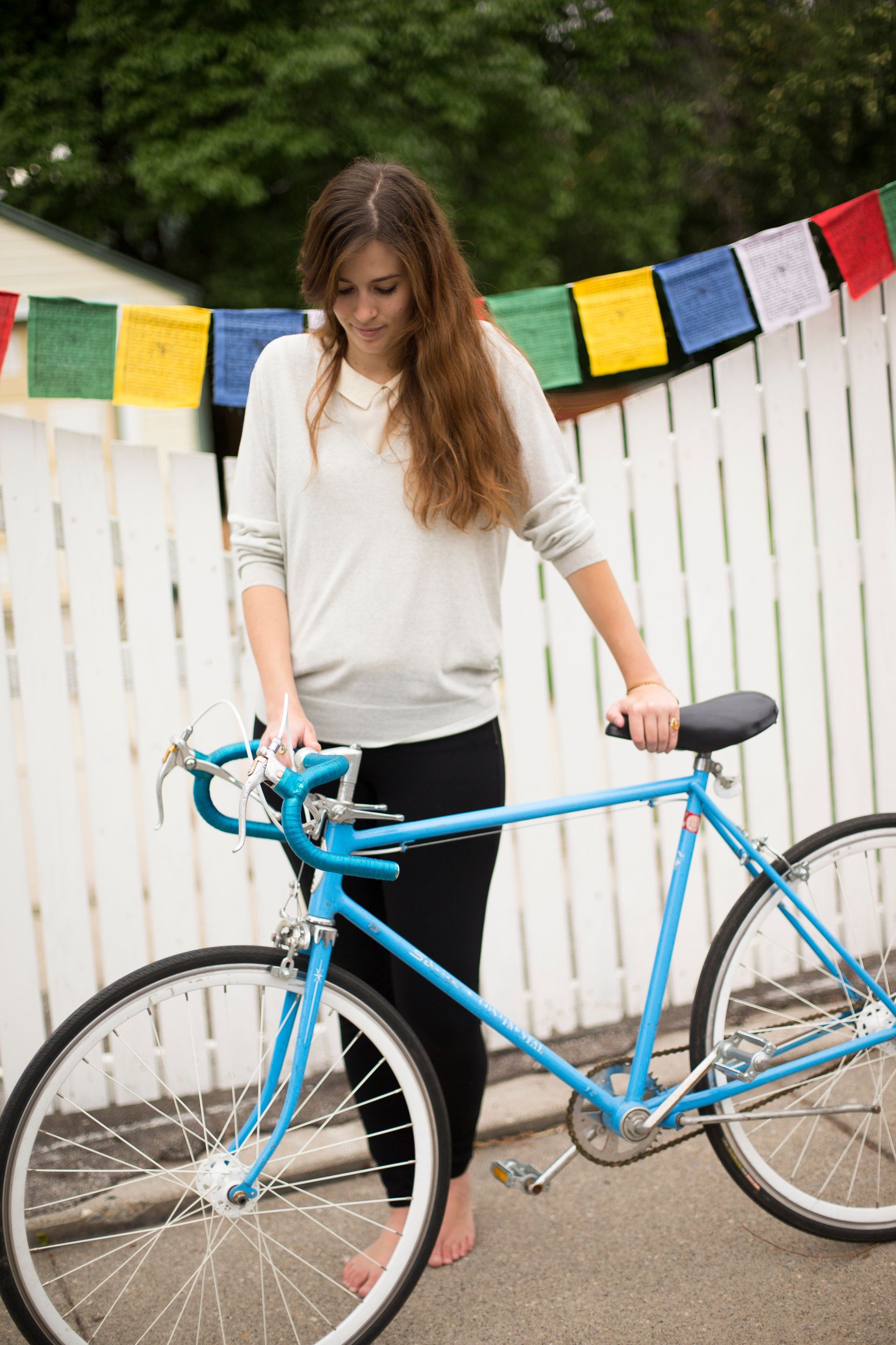 A woman walks along with her bike.  