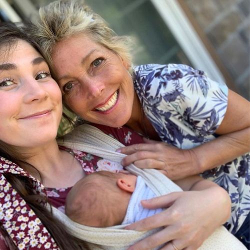 two women smiling while one holds a baby