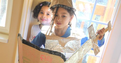 Children play dress up with homemade armor of sword and shield.