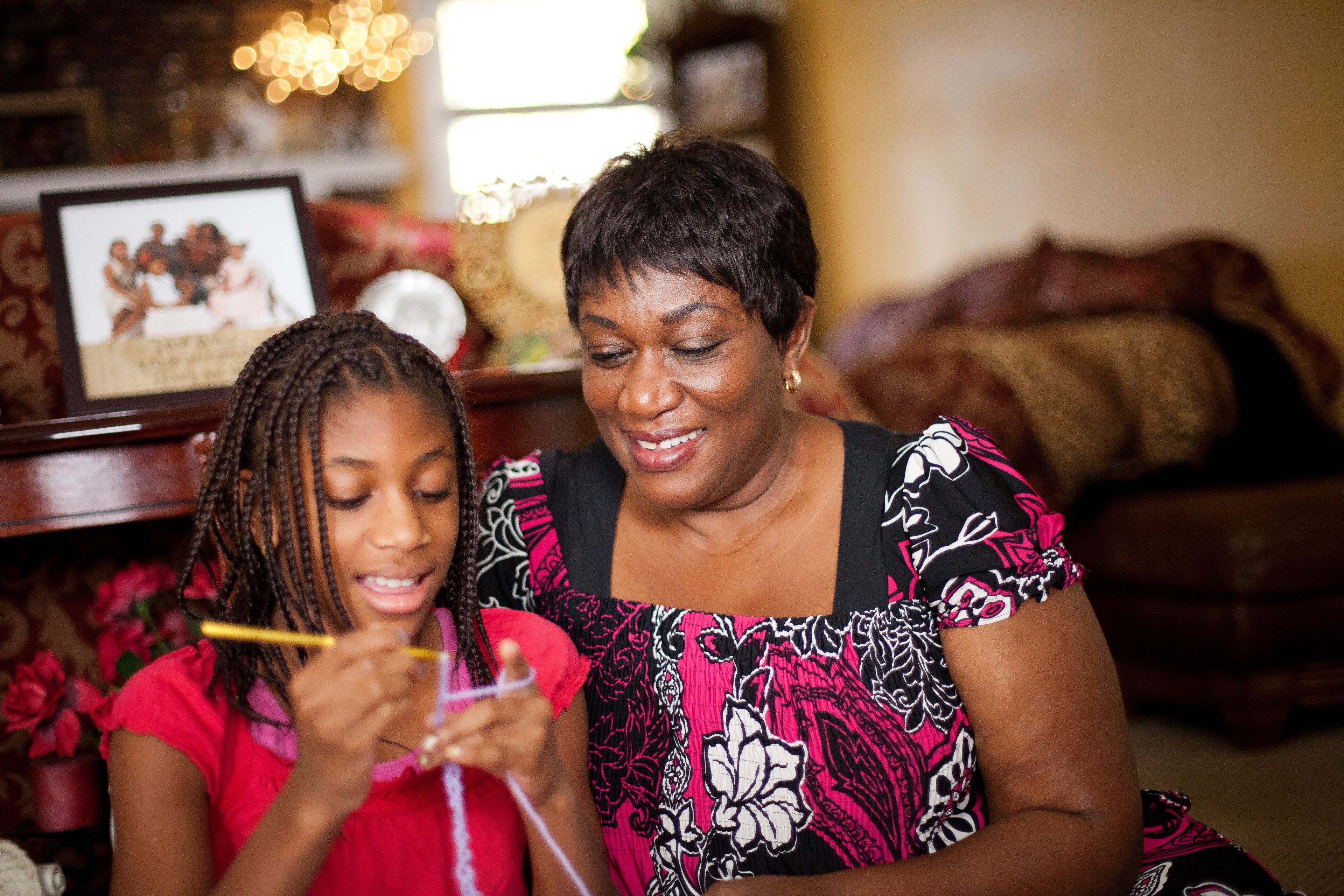 A mother shows her daughter how to crochet.