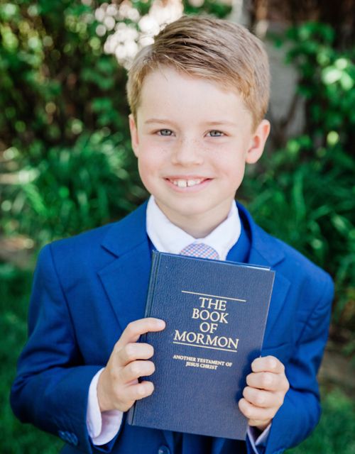 boy holding up Book of Mormon