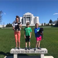 three children standing on bench in front of temple