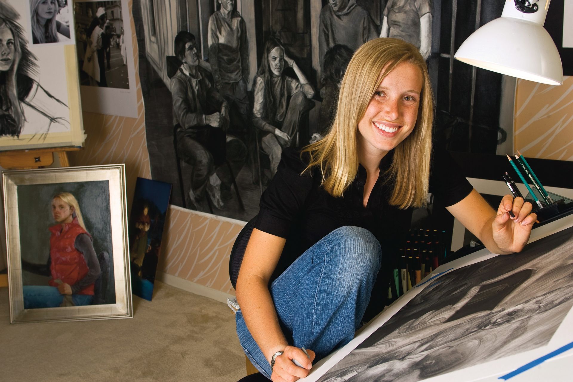 A young woman sits in her art studio and draws with charcoal.