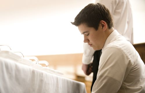 Priest kneeling in prayer at the sacrament table.