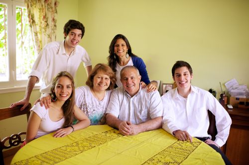 A mother and father sit at the dining room table with their four grown children.