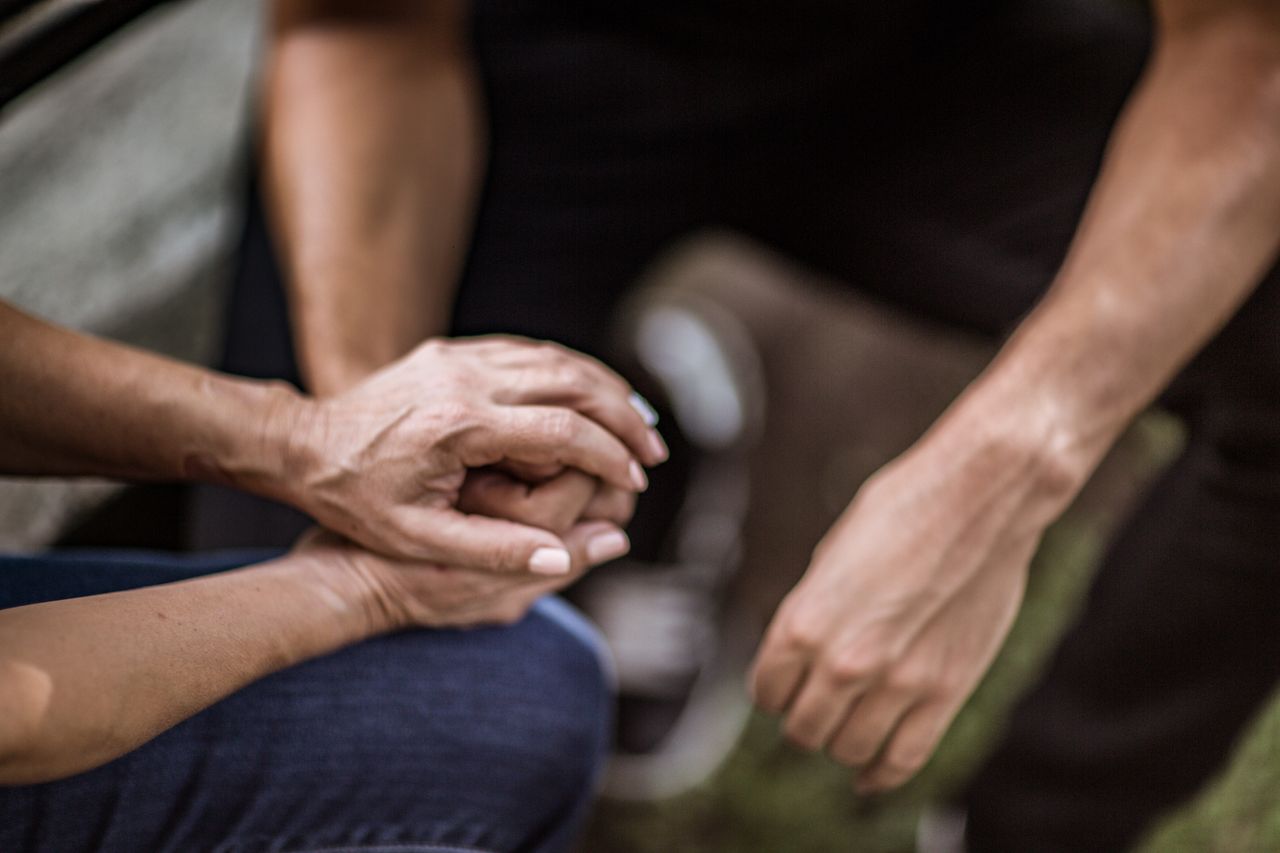 A young man holds the hand of an older woman