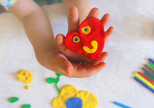 Child holding a heart shape made of playdough