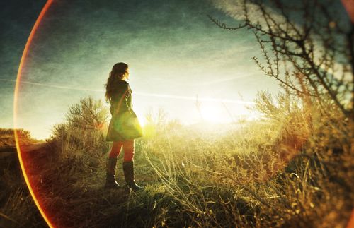 girl standing in a field at sunset