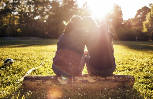 two people sitting together on a log