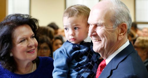 Elder Russell M. Nelson holds young boy during his apostlic travels in Brazil 2014.