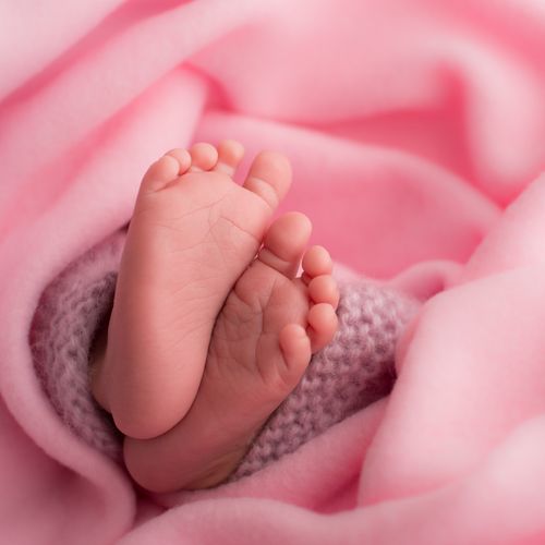 A baby’s feet wrapped in a pink blanket.