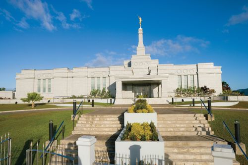 The front entrance to the Suva Fiji Temple during the daytime, with the stairs on the grounds leading to the entrance.