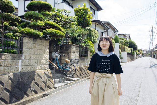 A young woman (Rikuto Ishida) smiles to camera while taking pictures.
