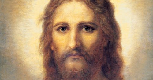 Frontal head and shoulders portrait of Jesus Christ. Christ is depicted wearing a pale red robe with a white and blue shawl over one shoulder. Light emanates from His face.