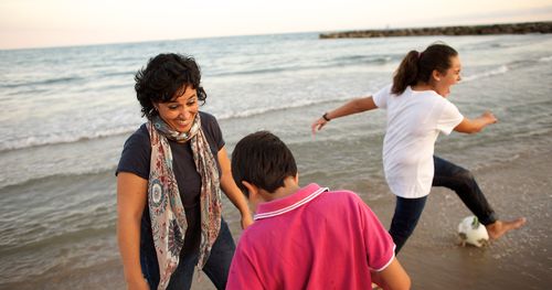 woman and two children playing on a beach