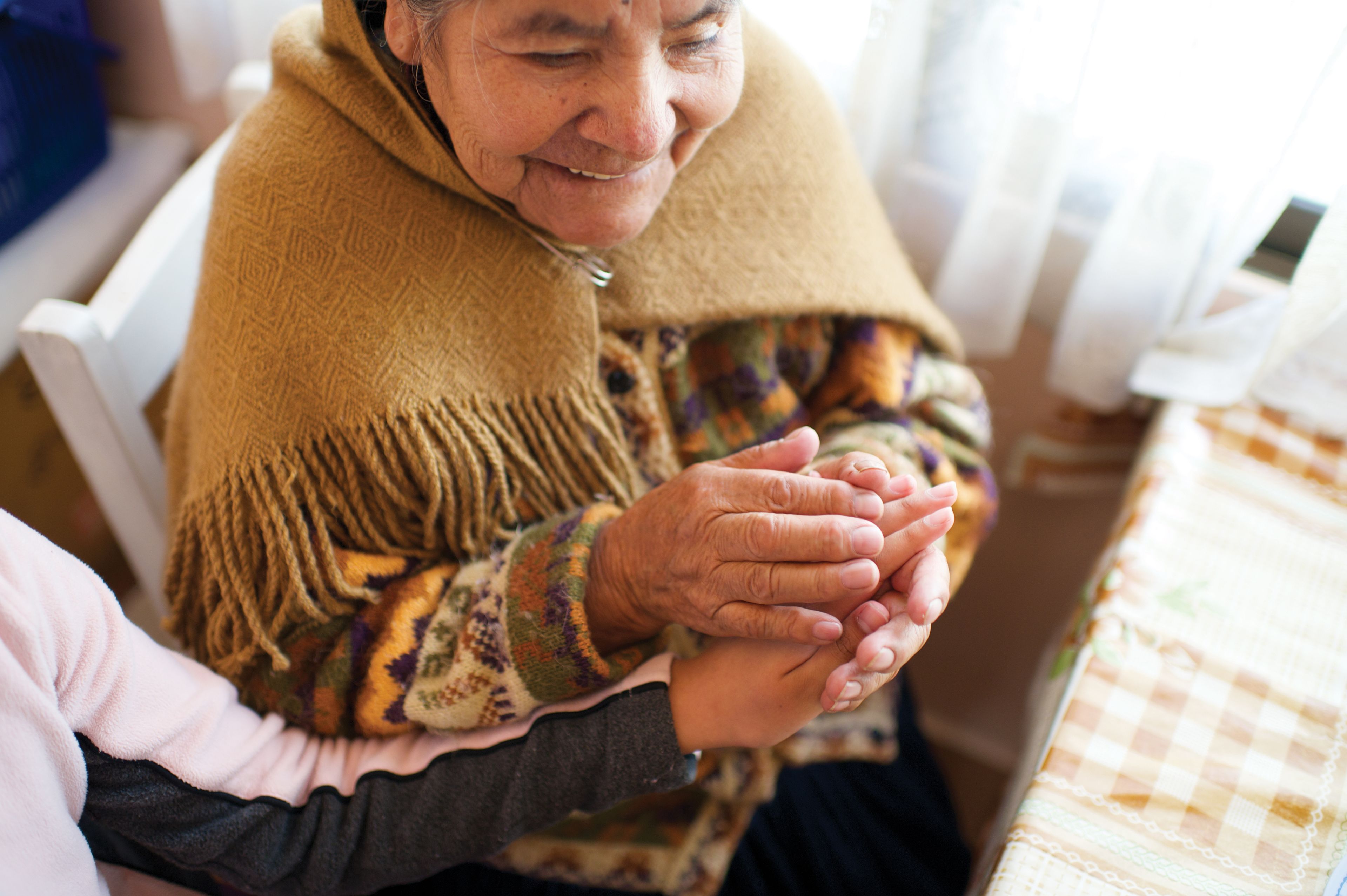 An elderly Bolivian woman holding the hand of a young girl.