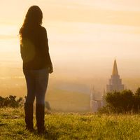 Young woman standing on a hill overlooking the Oakland Temple