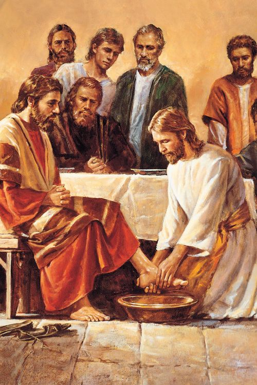 Jesus Christ with the twelve apostles. Christ (depicted wearing a white robe with a yellow sash), is kneeling before one of the apostles as He washes the feet of that apostle. The other eleven apostles are gathered around a table (having just completed the last supper). They are watching Christ. (John 13:1-20)