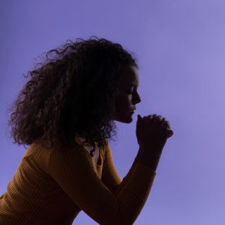 A young woman kneels in prayer