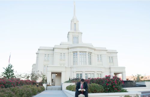 a young man reading his scriptures outside the temple