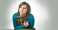 A young adult woman holding a framed print of Hofmann's Christ potrait.