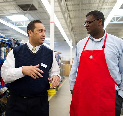 man with apron and a man with sweater talking