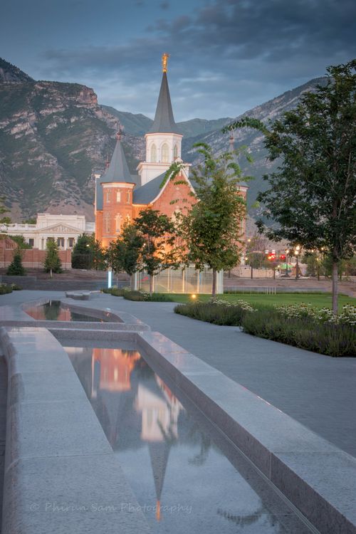 Reflecting pools and trees leading up to the Provo City Center Temple, with mountains in the background.