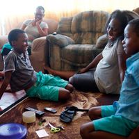 South Africa.  Family spending time together playing a memory game.  Boy about to guess what is missing.