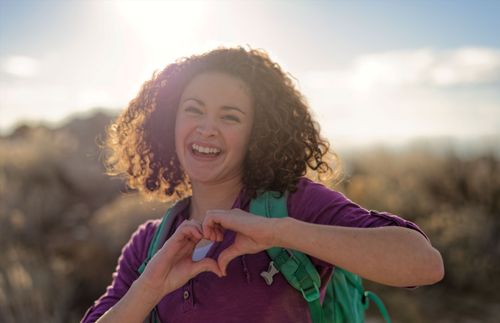 smiling young adult woman making heart shape with her hands