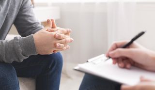 Therapist writing notes during counseling session with single man