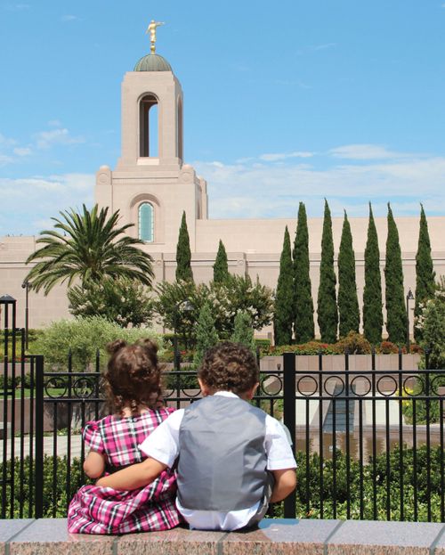 Una niña y un niño sentados frente al templo