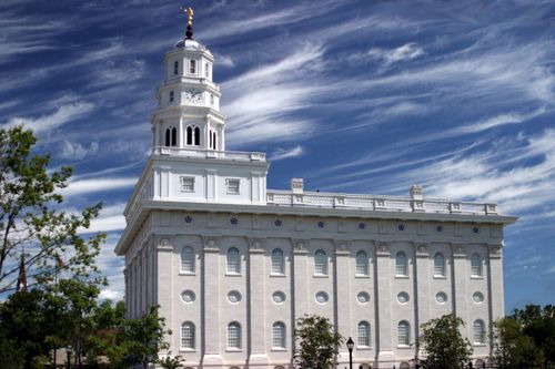A side view of the Nauvoo Illinois Temple on a sunny day, with a bright blue sky and some thin clouds overhead.